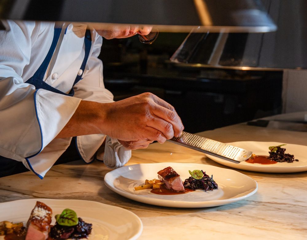 A chef finishing a plated Mediterranean dish