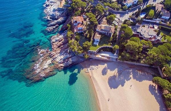 Aerial view of turquoise water and a sandy cove on the Costa Brava