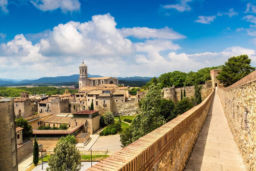 The medieval walls and cathedral of Girona under a blue sky