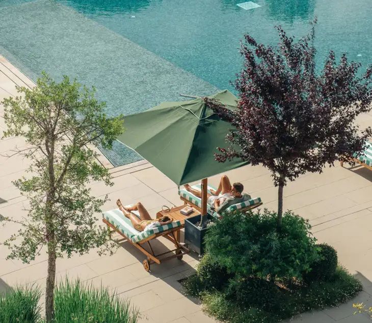 Loungers under a green umbrella beside the outdoor pool