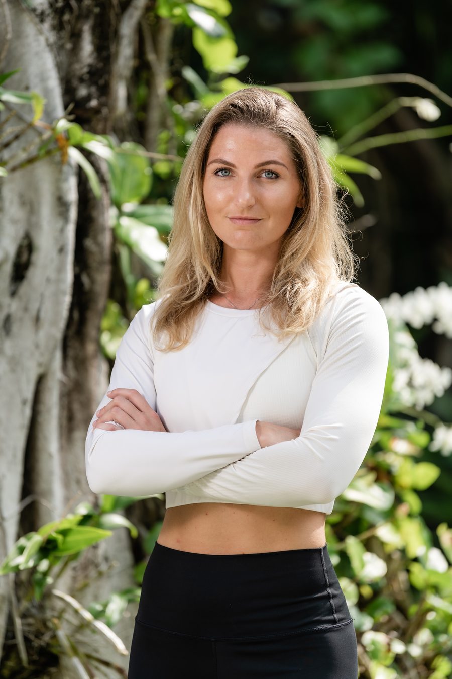 Portrait of Simone Estelle, arms crossed, in a tropical garden